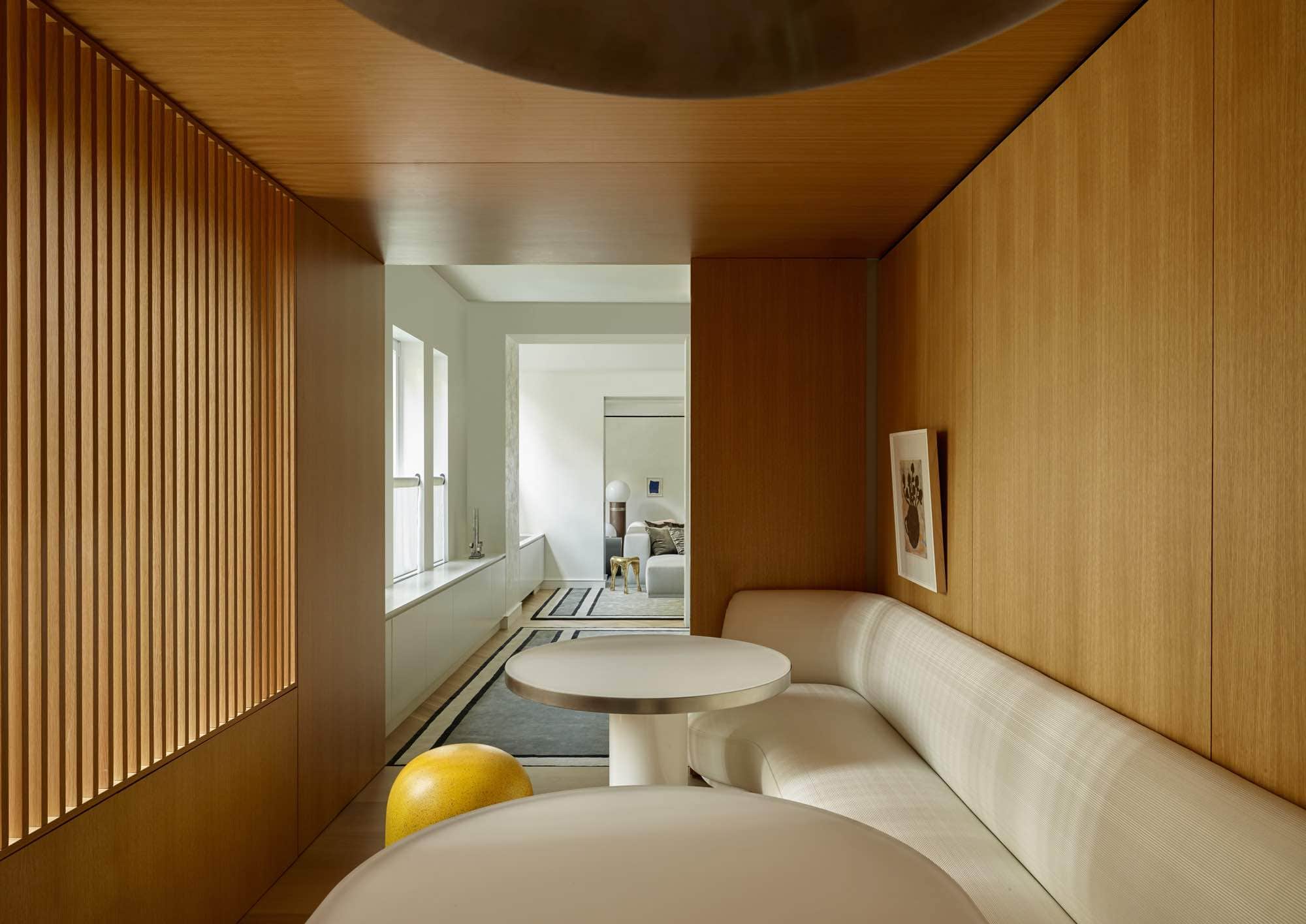 Designed by Carol Egan are two dining room tables in 3Form Chroma Engineered Resin, one circular and one racetrack in shape positioned in front of a custom fitted banquette in the breakfast room.  A yellow Puffo stool by Gruppo Sturm is seen in the image around the smaller circular dining table.  Etching: "6 Flowers" by Donald Baechelor hangs low above the banquette.