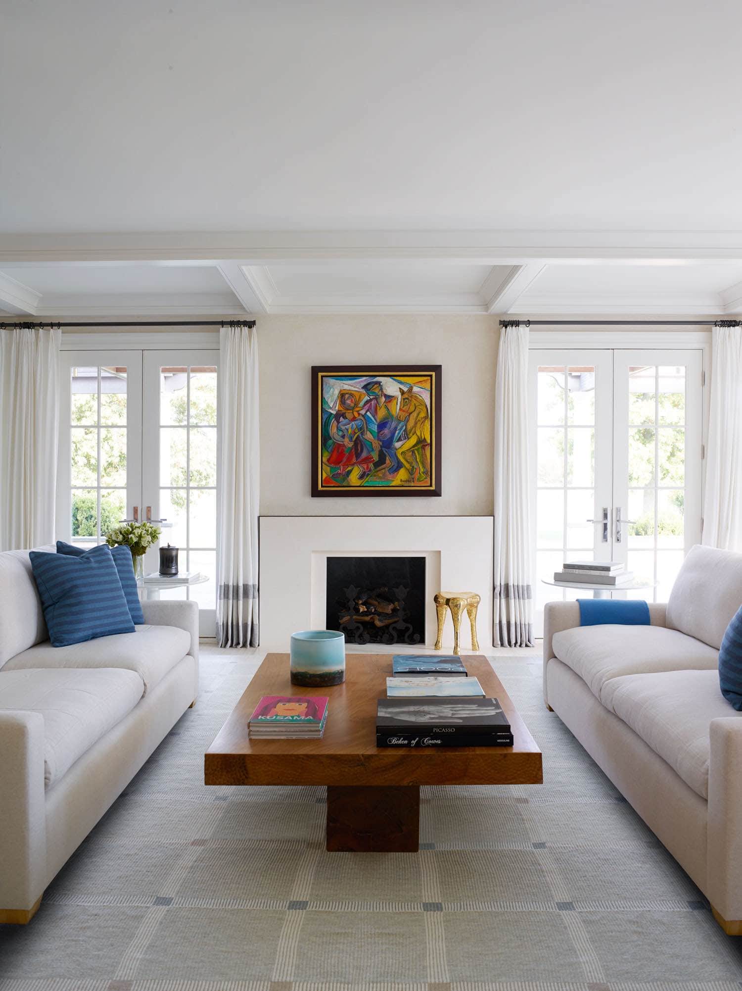 Peasants and Horse’, oil on canvas by David Burliuk is the painting featured above the fireplace in this living room designed by Carol Egan.  Two sofas in white linen upholstery flank a pedestal coffee table by Tucker Robbins.