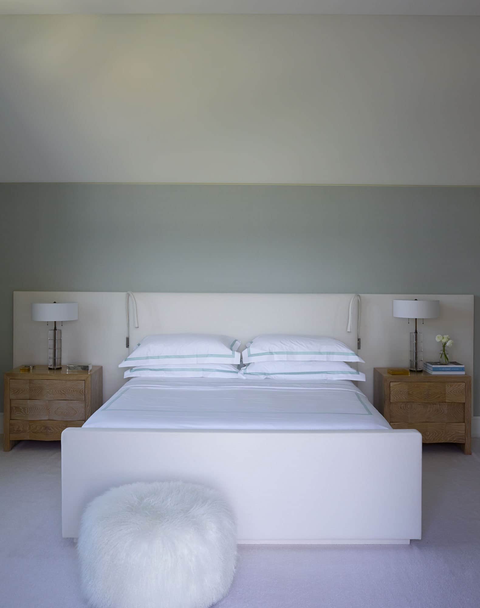 Designed by Carol Egan, this image shows a master bedroom with upholstered walls in custom "Jed’s Pale Blue Silk" fabric by Sam Kasten.  There are a pair of JMF Style cubist nightstand by Tucker Robbins with polished crystal table lamps by Lianne Gold, custom upholstered bed design by Studio Carol Egan, Ecru fabric for bed Upholstery by Loro Piana, custom mohair area rug by Sacco Carpet, bronze boxes by Line Vautrin accessorize the bedside tables.