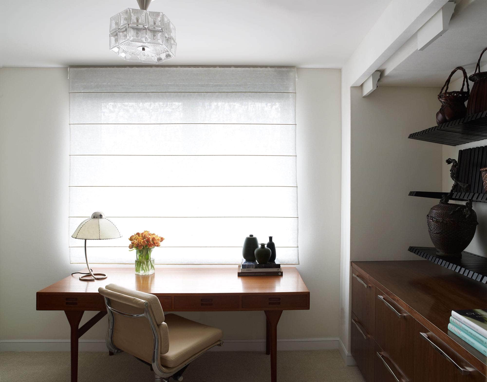 Designed by Carol Egan, this image shows a petite study with a Nana Ditzel teak desk and Piano wall Shelf unit designed by Sebastian Errazuriz which houses an antique Japanese woven basket collection.  The desk chair is upholstered in camel leather and is an armless Eames desk chair.
