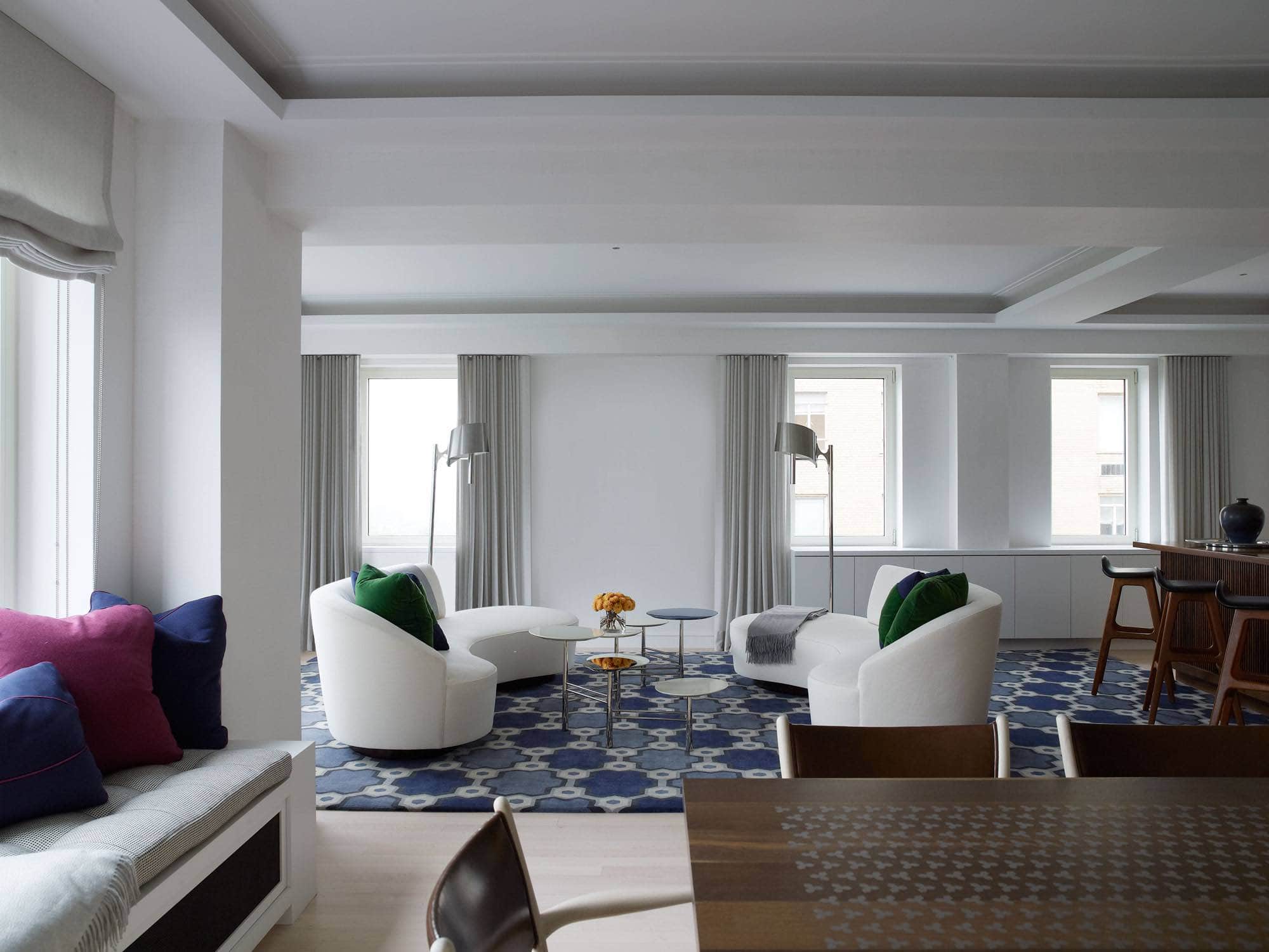 Designed by Carol Egan, this view of the living room shows wall treatment in a decoratively painted Strie patterned plaster with matte varnish finish coat and window treatment in Senorita Silver fabric by Holland & Sherry.  The living room has two white serpentine shaped sofas and a blue and grey patterned area rug.