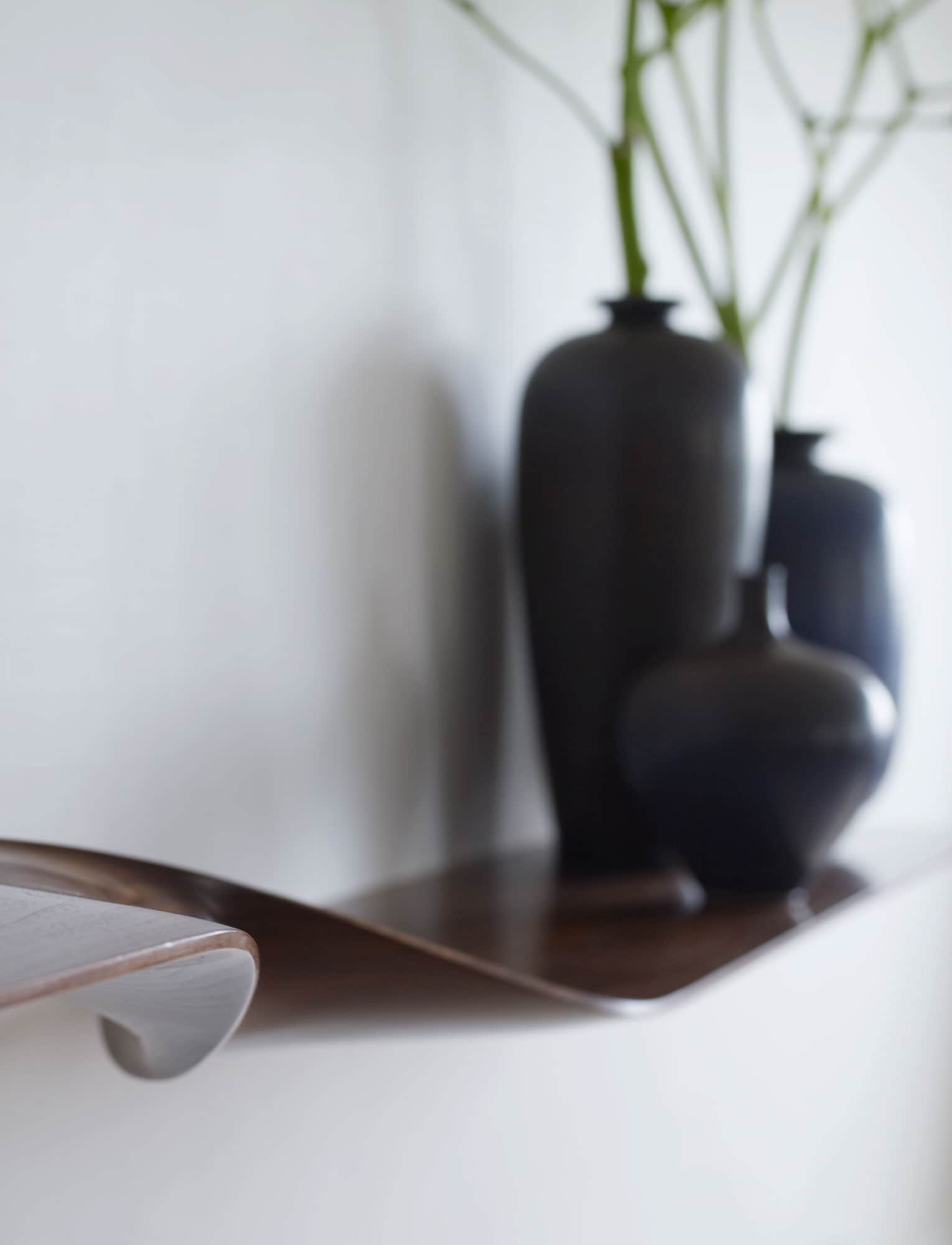 This image shows a wall hung CE01 180 Twist Shelf in a Walnut by Studio Carol Egan displaying vases by Berndt Friberg.