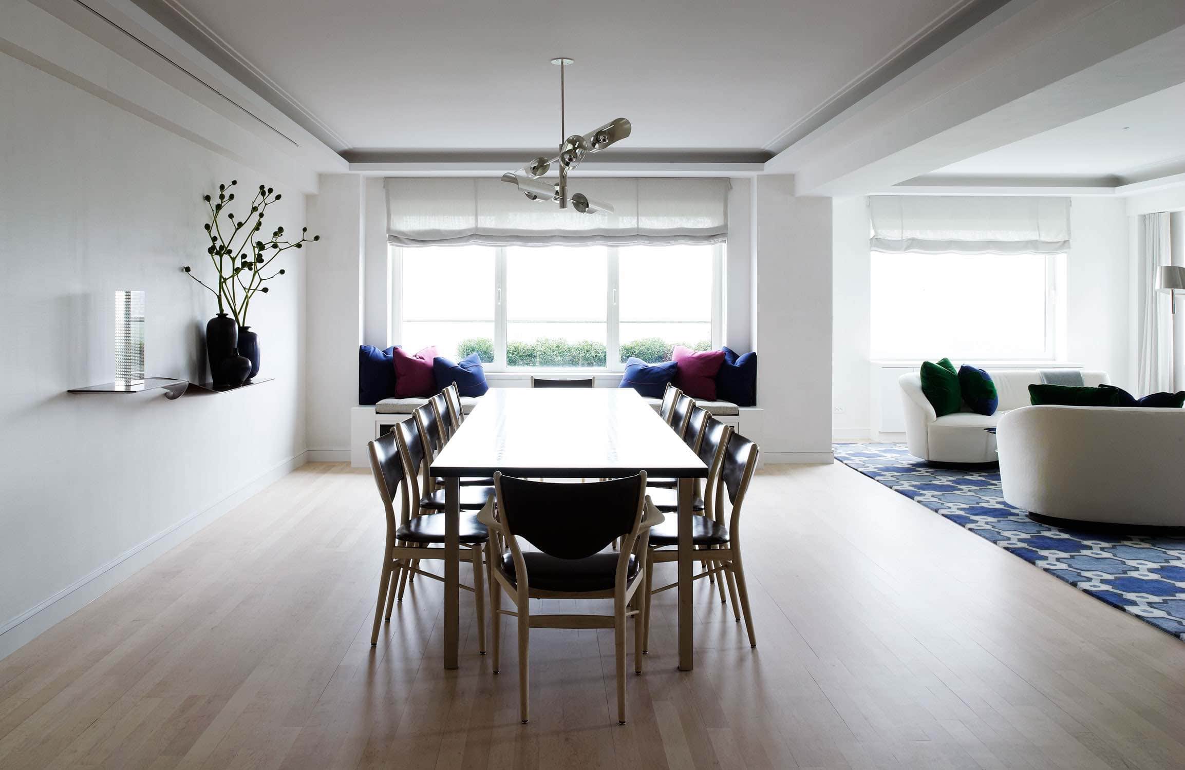 In this kitchen designed by Carol Egan, the PK 15 chairs by Poul Kjaerholm surround a round marble-topped table.  The area is lit with an Italian Mid-century chandelier and the kitchen cabinetry is walnut paneled doors accented by white marble counter tops.