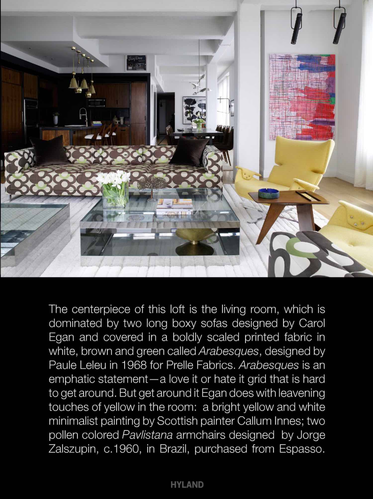 Photograph shown of a living room with custom sofa design by Studio Carol Egan in Prelle fabric by Leleu, glass and steel coffee table by Joe D’Urso.  Walnut kitchen units are offset by 50s brass Paavo Tynell pendant lights. Inteiror design by Carol Egan.